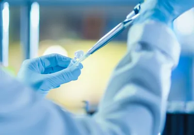 blue-gloved hands pipetting from test tube